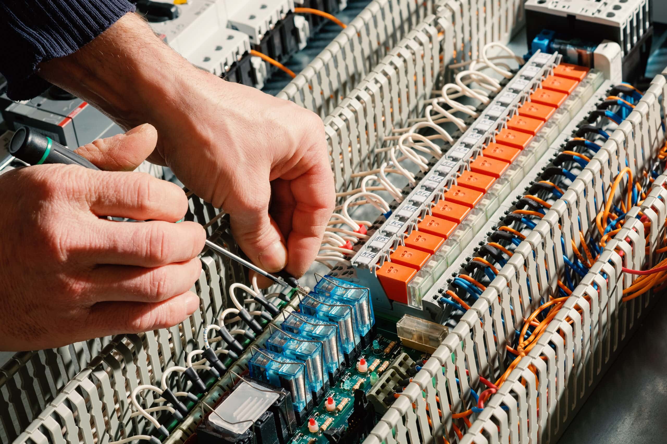 Close-up of an electrician working on the set up of a control cabinet.