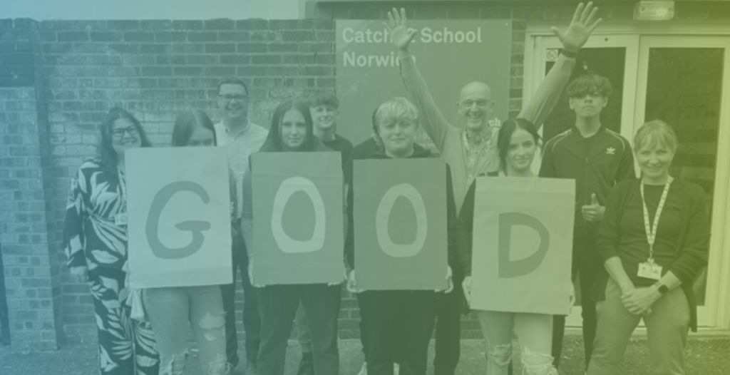 A group of students and teachers hold up letters spelling "good" in front of Include Norfolk school.