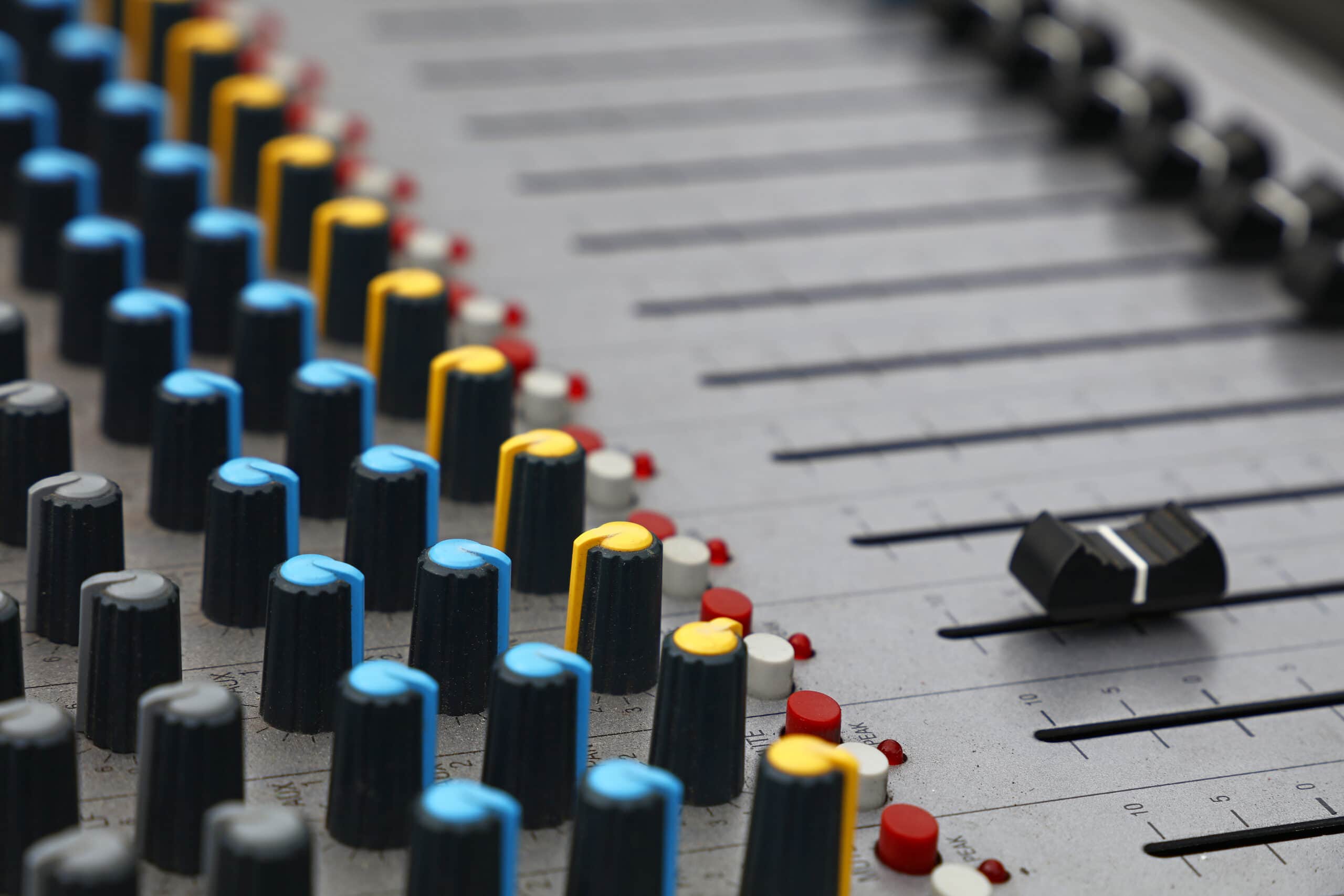 Close-up of audio control sound mixing console board with fader bars, buttons and sliders.
