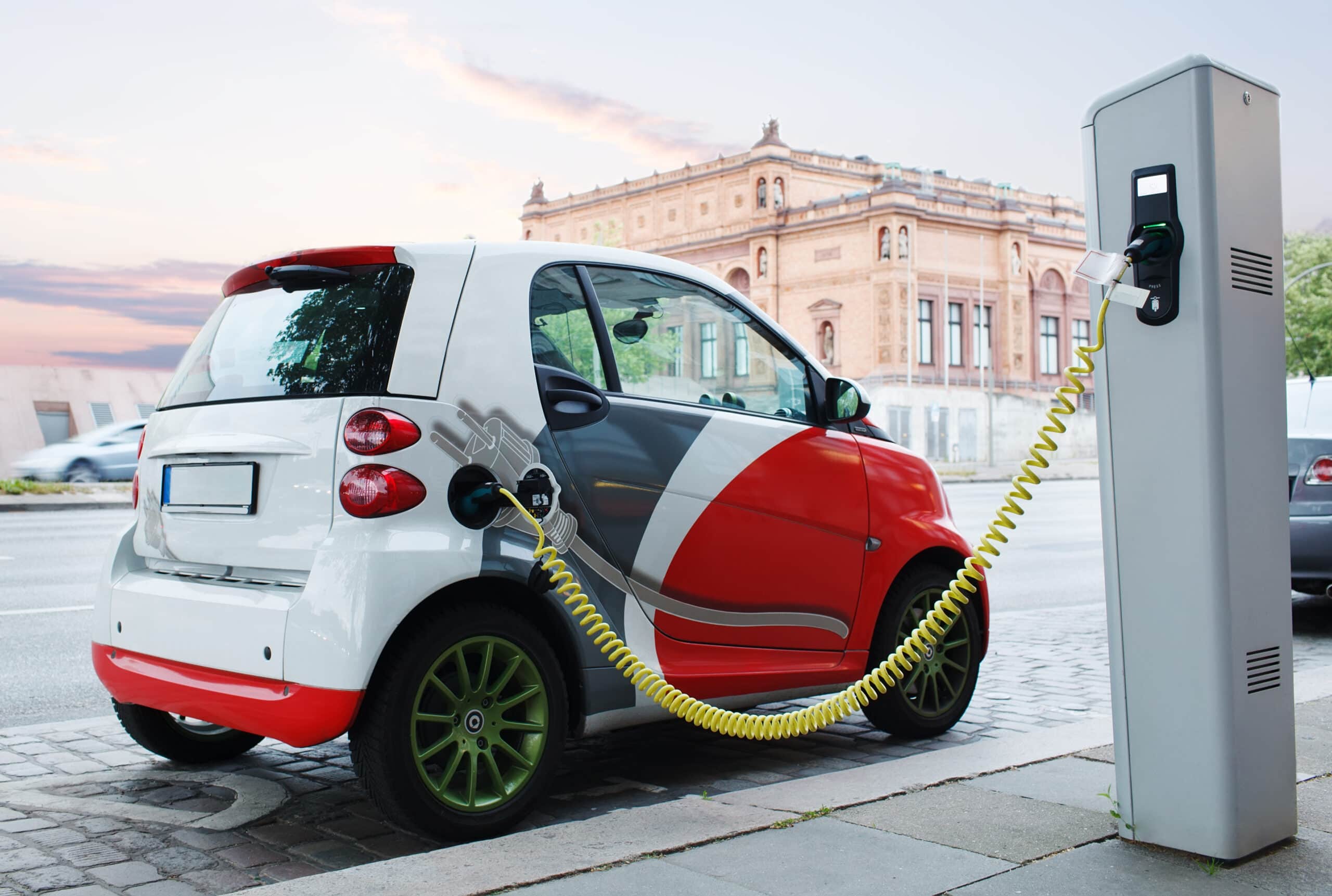 An electric city car charges in the street.