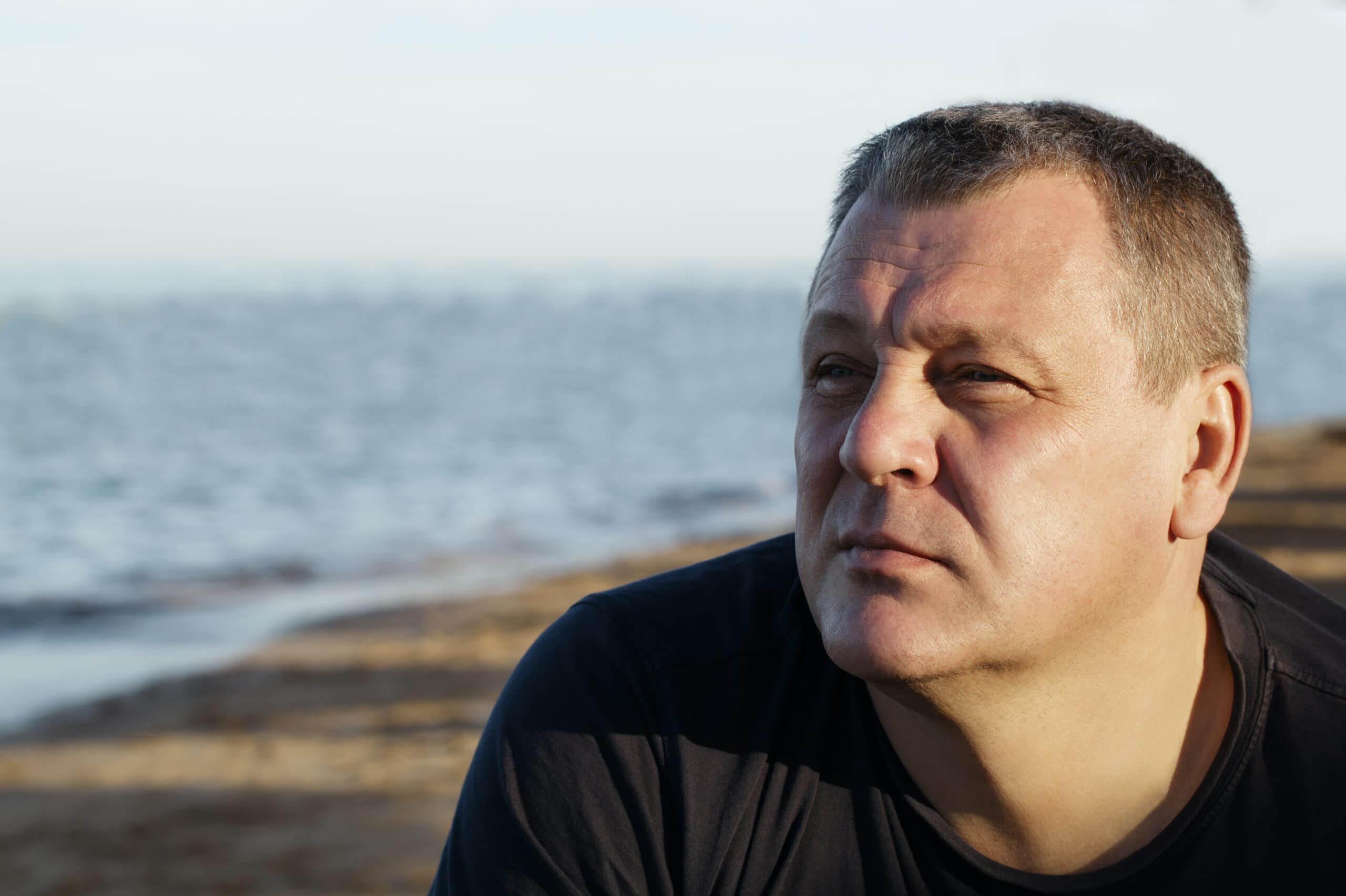 Portrait of a middle-aged man looking away from the camera on a beach.