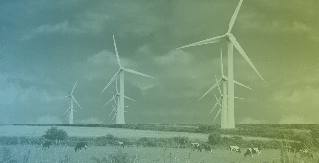 Wind turbines stand in a field in the countryside.