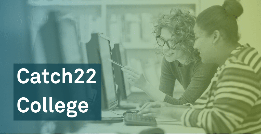 Two students smile as they work together at a computer. They are sat in a library and other computers can be seen in a row. One is sat in a chair, and the other is leaning over pointing to something on the screen. Overlaid is text that reads: "Catch22 College".