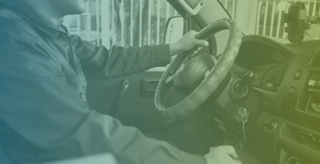 Close-up of a man driving a large van. One hand is on the steering wheel, and the other on the gearstick.