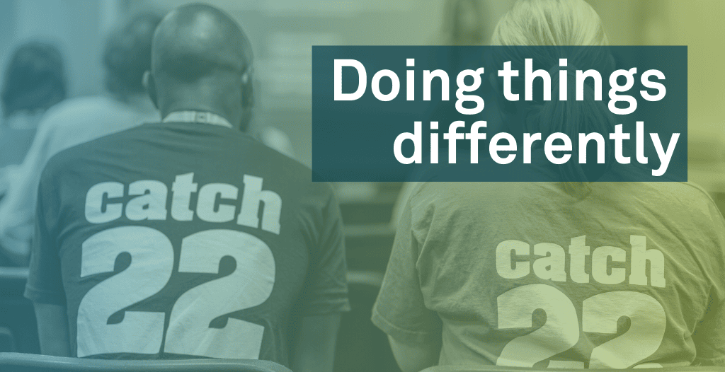 A man and a woman sit in chairs with their backs to the camera. They are both wearing t-shirts with the Catch22 logo on the back. Overlaid is text that reads "Doing things differently".