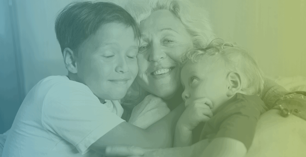 Close-up of a grandmother being hugged by her two young grandchildren.