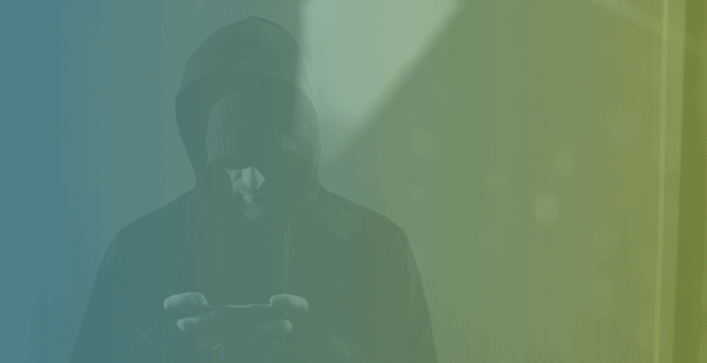 A hooded figure browses content on their phone.