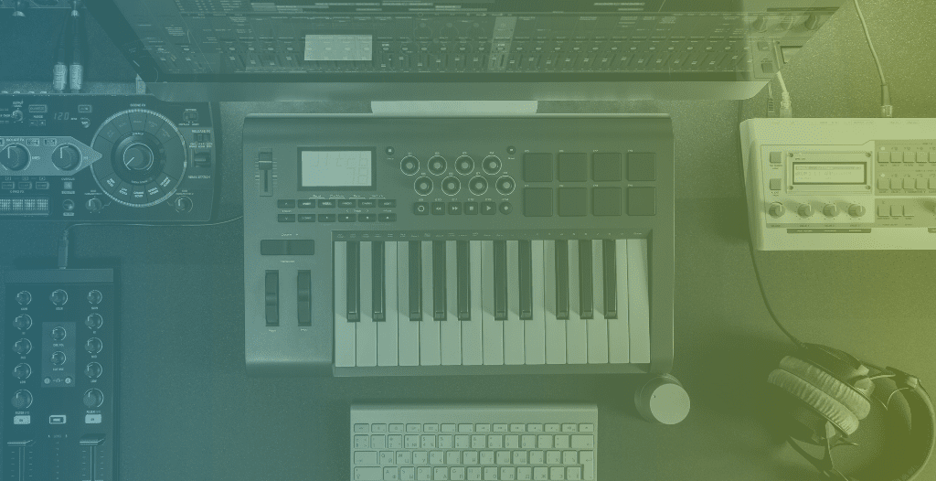 Overhead view of a music studio set up including keyboard, headphones and computer screen.