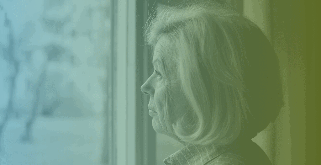 A mature woman looks out of a window,
