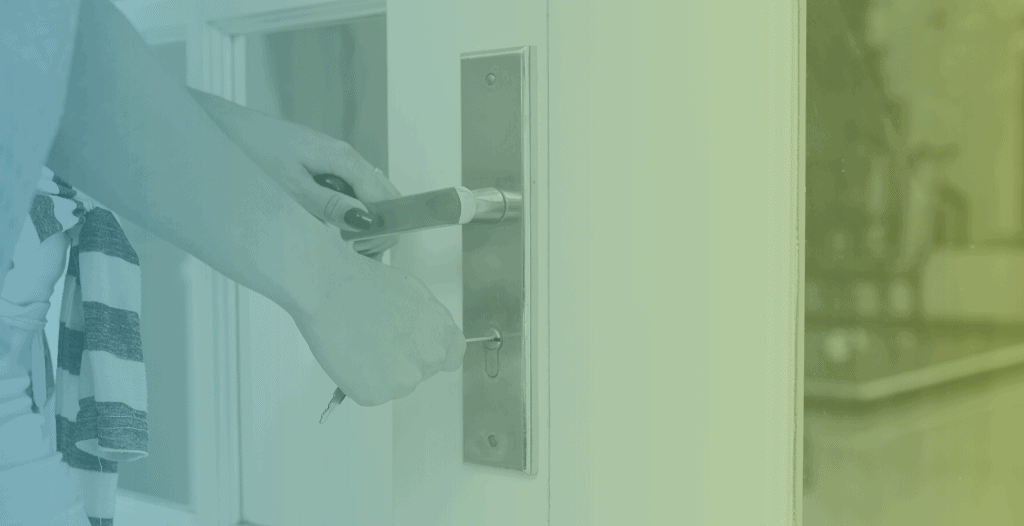 Close-up of hands unlocking and opening a door using a key.