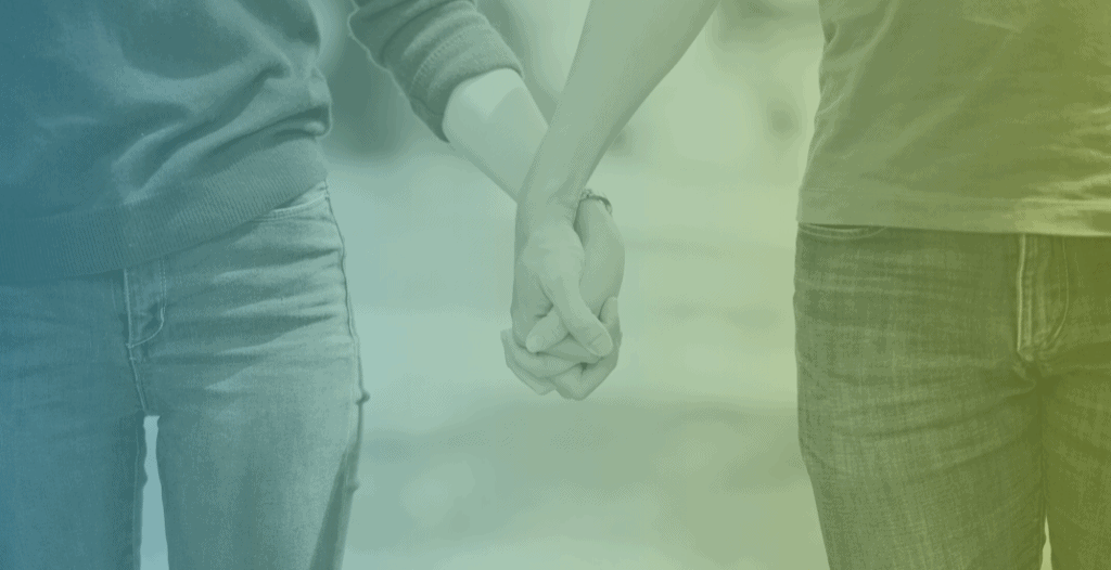 Close-up of two people holding hands.